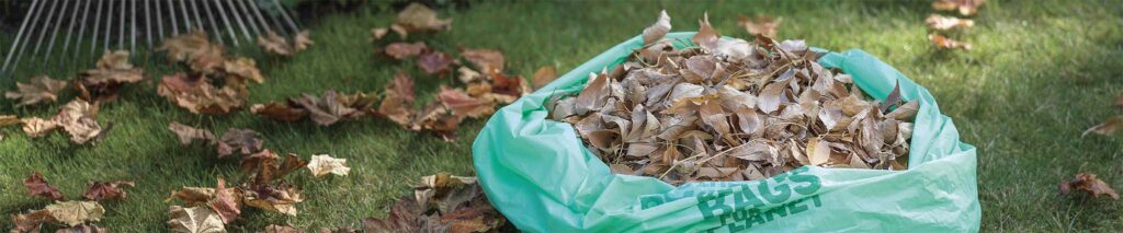 compostable lawn and leaf bags filled with yard waste in garden setting